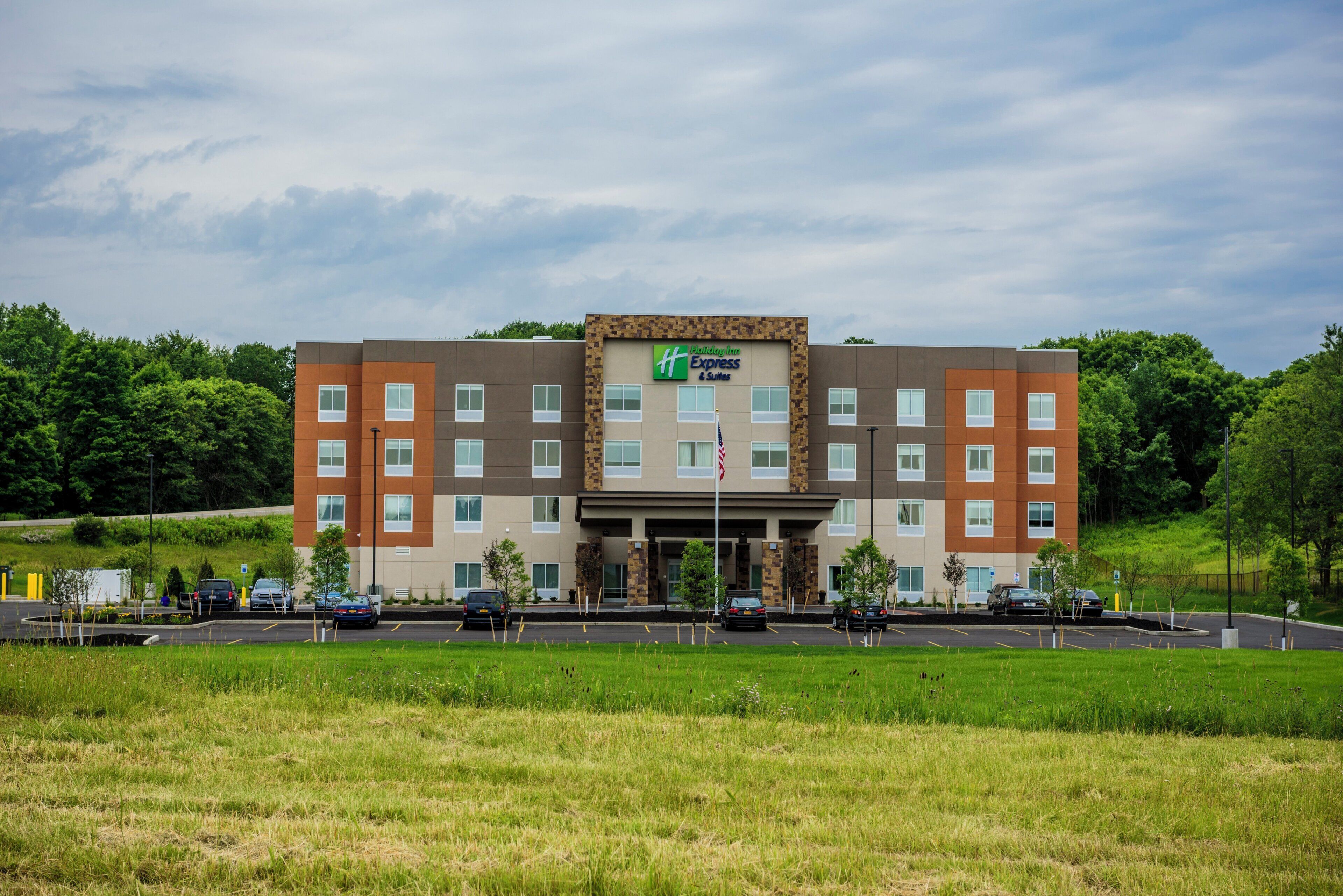 A Holiday Inn Express & Suites hotel with a modern design, featuring a flat roof and a mix of brown and beige exterior walls.