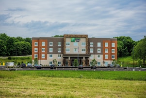 Un hotel Holiday Inn Express & Suites de diseño moderno, con techo plano y paredes exteriores en tonos marrones y beige.