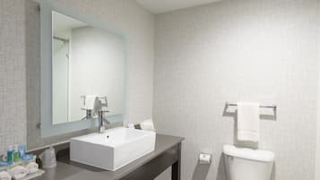 A modern bathroom with a large mirror, a white sink, and a toilet.