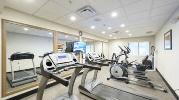 A fitness center with treadmills, ellipticals, and a mirrored wall.