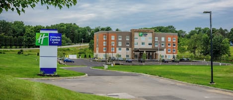 A Holiday Inn Express & Suites building with a parking lot and a grassy area in front.