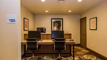 A business center with two desks, chairs, and a computer.