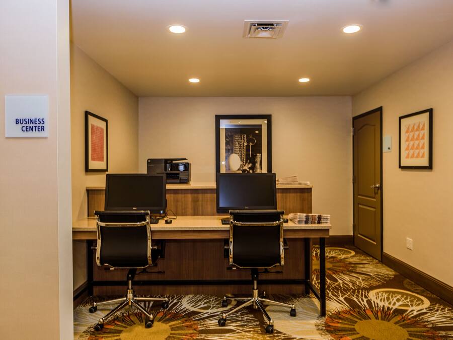A business center with two desks, chairs, and a computer.