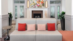 Una sala de estar moderna con chimenea, dos sofás y un cuadro floral grande sobre la repisa.