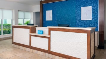 A hotel reception desk with a blue textured wall, framed artwork, and a 'Hilton' sign.
