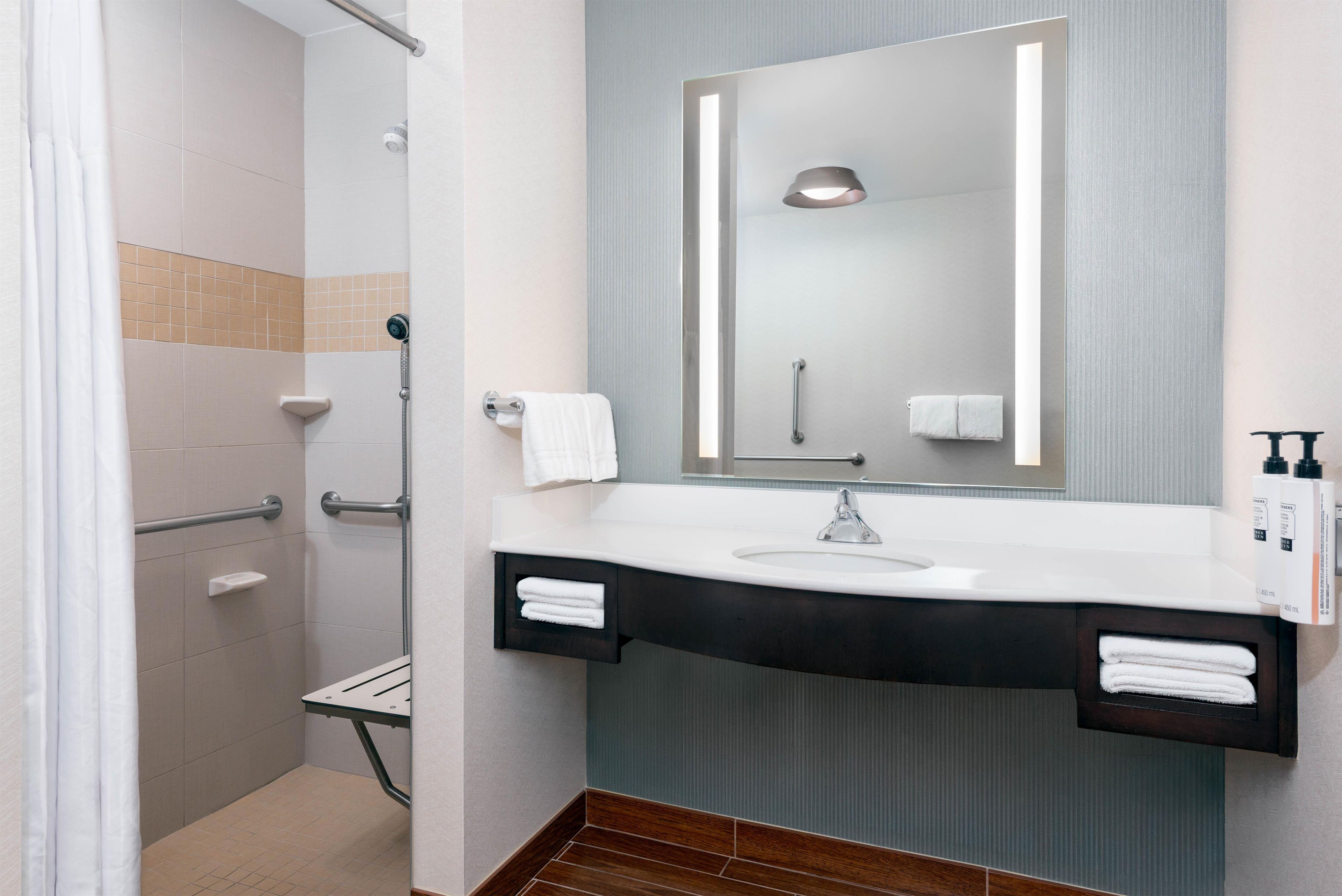 A modern bathroom with a shower, a sink, and a mirror.
