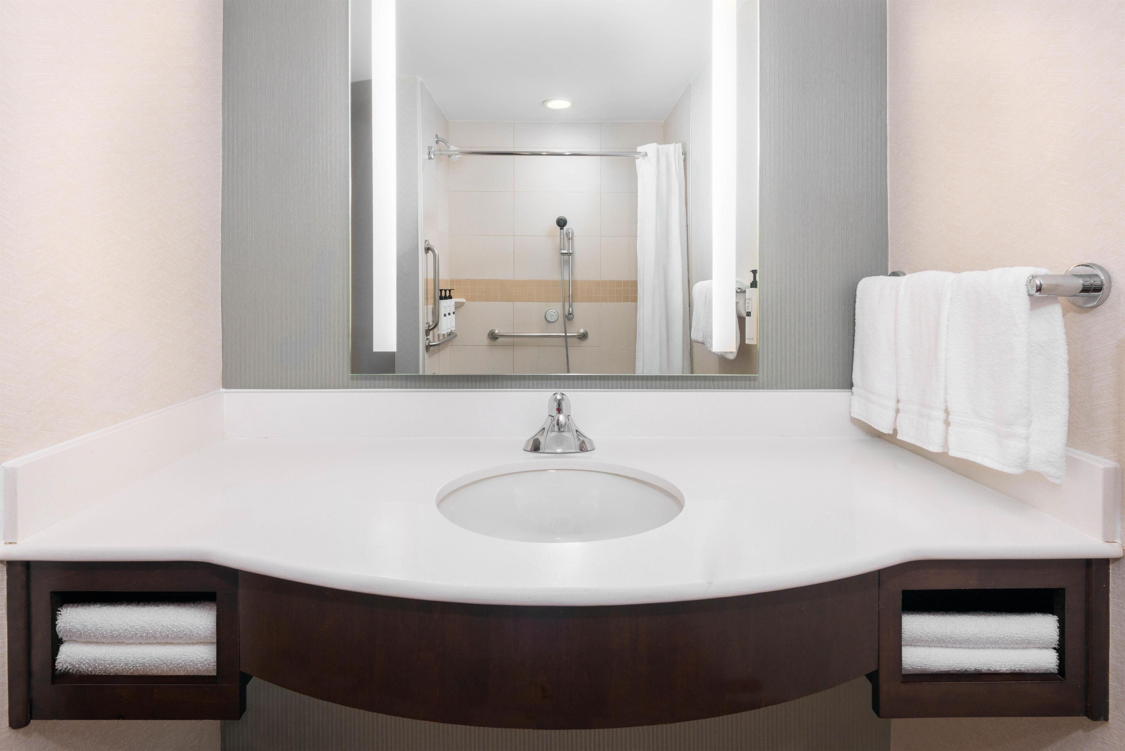 A bathroom with a white sink, mirror, and two towel racks.
