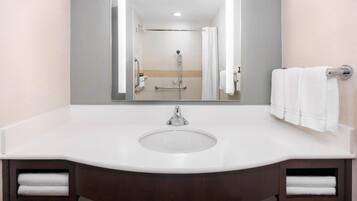 A bathroom with a white sink, mirror, and two towel racks.