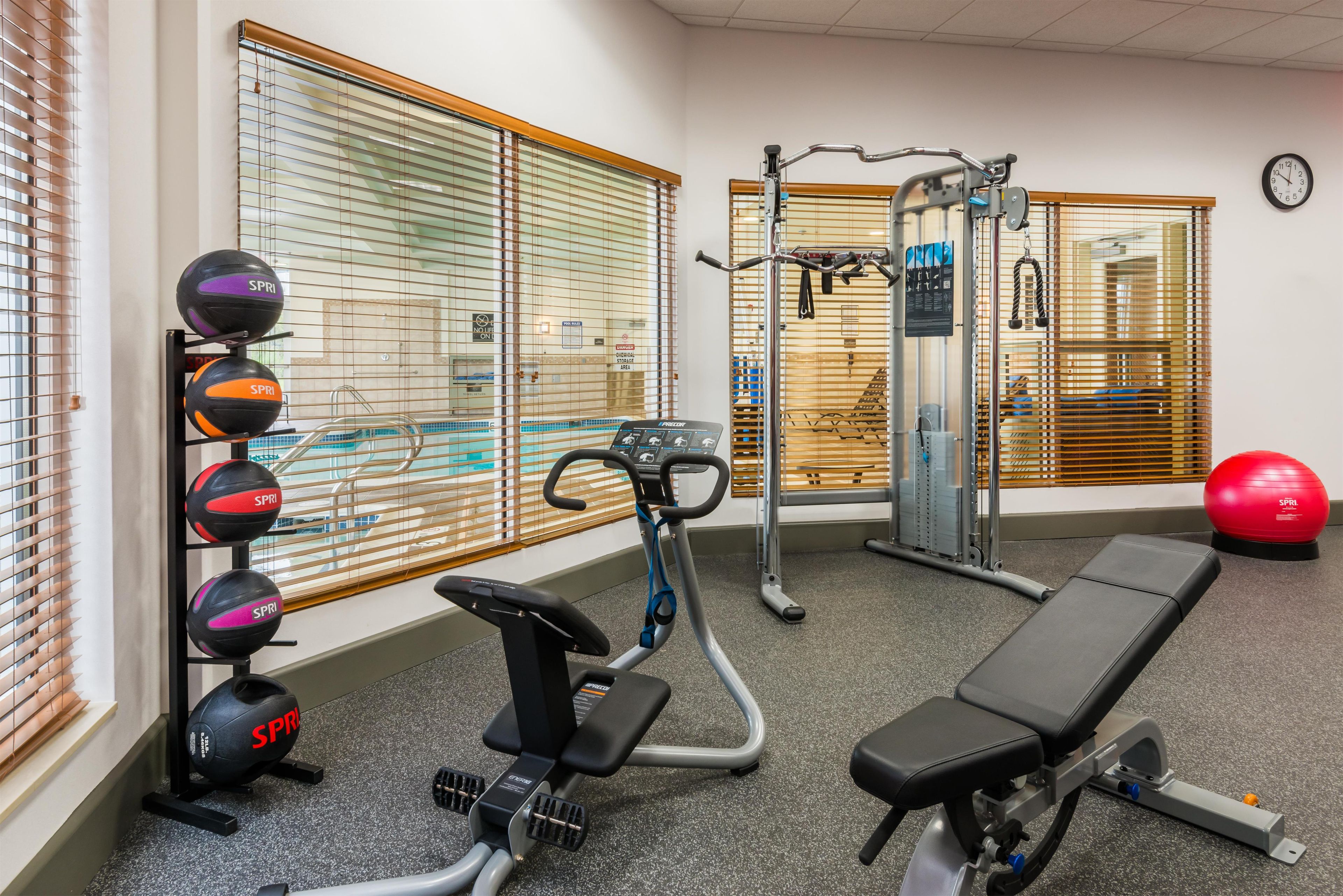 A gym with exercise equipment, a bench, and a wall clock.