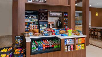 A snack and beverage kiosk in a shopping area with a variety of snacks, drinks, and a coffee machine.