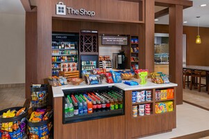 Un quiosco de aperitivos y bebidas en una zona comercial, con gran variedad de productos, bebidas y una máquina de café.