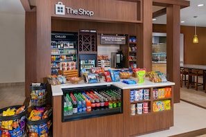 A snack and beverage kiosk in a shopping area with a variety of snacks, drinks, and a coffee machine. - Hilton Garden Inn Wayne (Wayne)