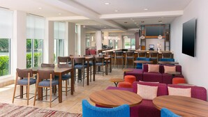 Un moderno vestíbulo de hotel con zona de bar, asientos y ventanas amplias.