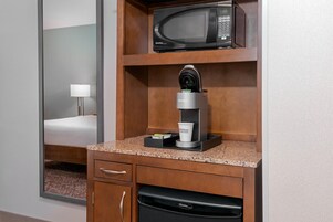 Una kitchenette con microondas, cafetera Keurig y una taza de café con la marca Hilton.