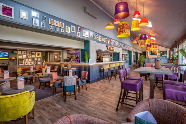 A restaurant with a bar area, multiple seating options, and a variety of colorful hanging lamps. - The Lodge Hotel (Coleraine)