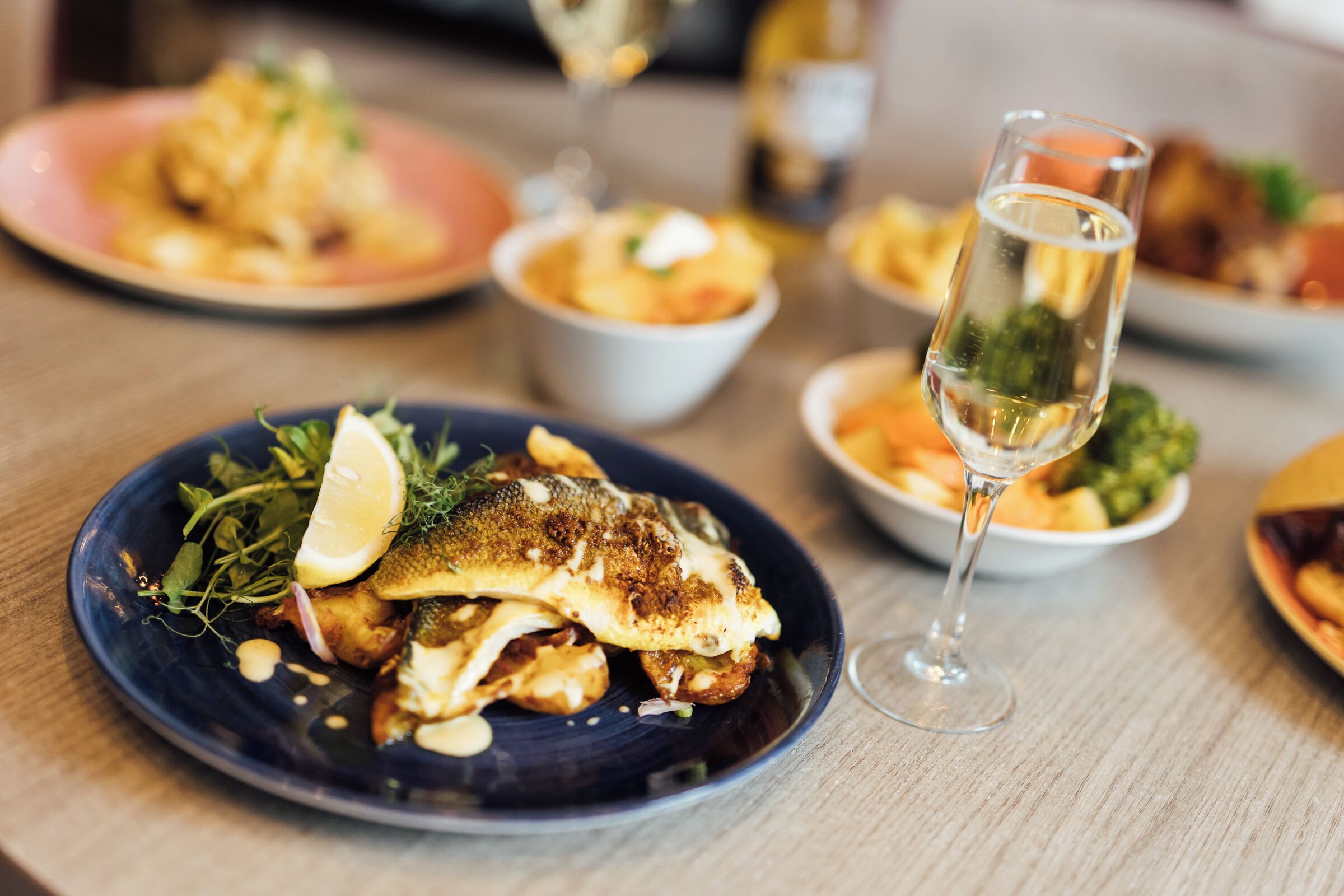 A dining table with plates of food and a glass of wine.