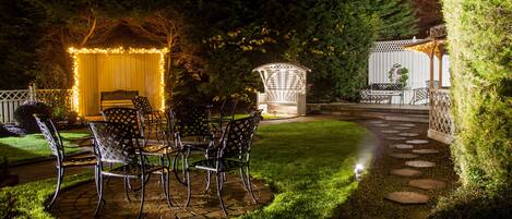 A patio area with a table and chairs, a wooden fence, and a garden path.