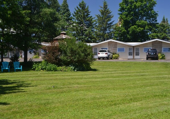 A residential area with two single-story houses, a grassy lawn, and a few parked cars. - Stratford Suburban Motel (Stratford)