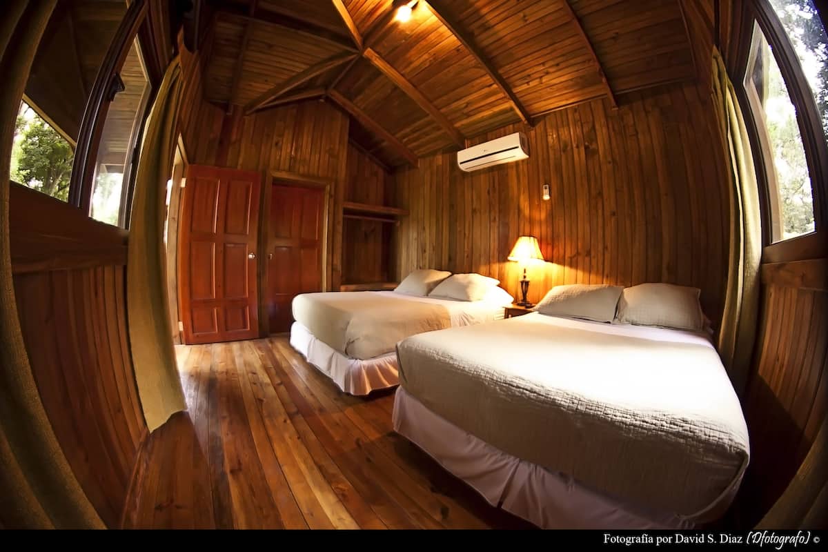 Une cabane en bois avec deux lits, une armoire et une lampe.