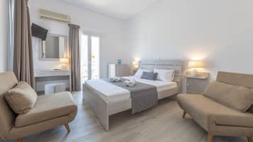 Una habitación de hotel moderna con cama, dos sillones, escritorio y televisión.