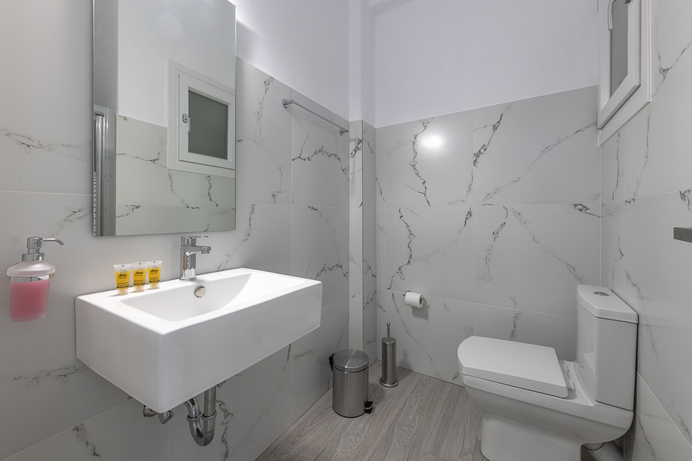 A modern bathroom with a white sink, mirror, and toilet.