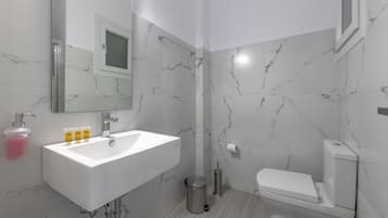A modern bathroom with a white sink, mirror, and toilet.
