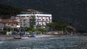 A coastal building with balconies, a beach, and boats.