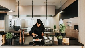 A modern kitchen with a chef preparing food, stainless steel appliances, and potted plants. -  Isabella Island Miramare Suites - Villas, Valamar Collection (Porec)