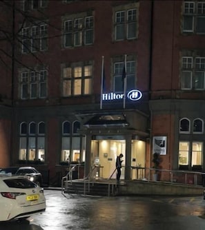 A hotel entrance with a visible sign, a person standing at the entrance, and a car parked in front. - Victoria Centre Apartments & Annexe (Nottingham)