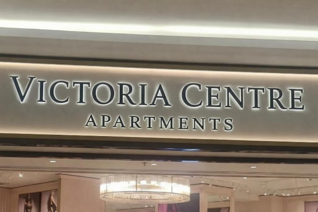 Señalización para 'Victoria Centre Apartments', con un diseño de interiores moderno, que incluye una araña y obras de arte enmarcadas.