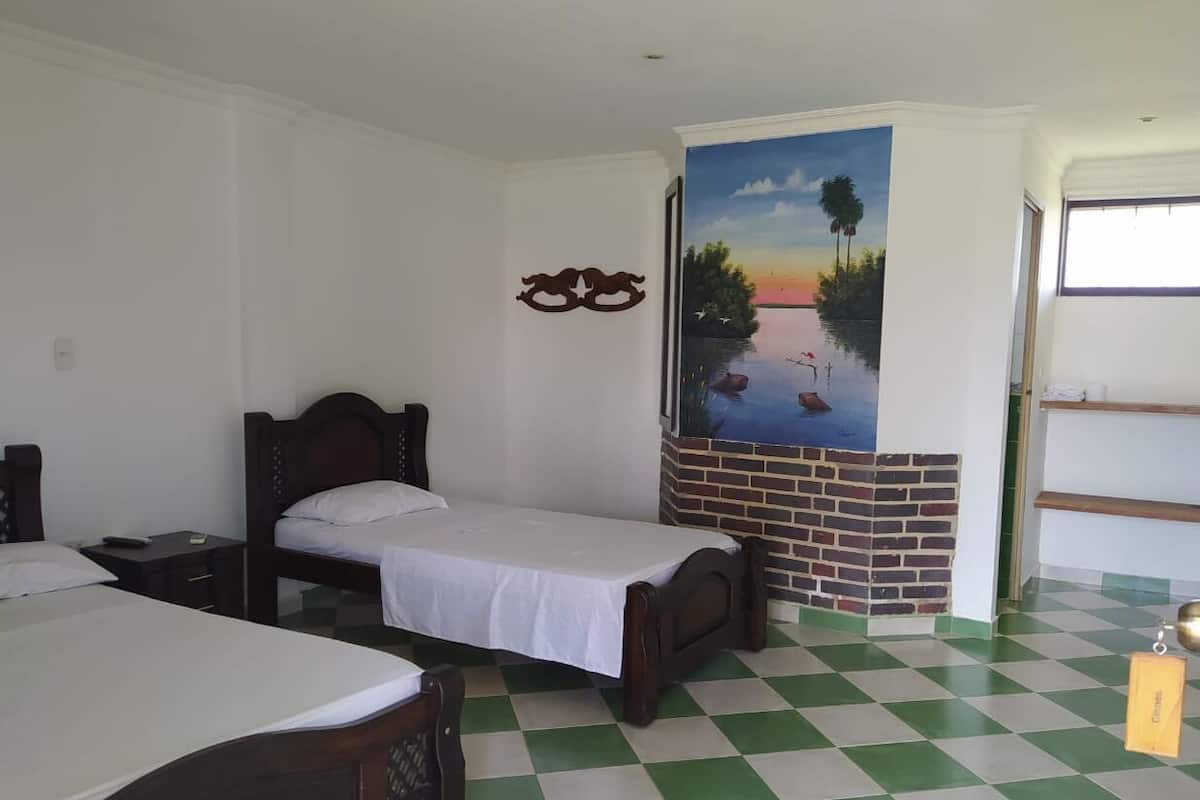 Una habitación con cama, escritorio y un mural de un atardecer sobre el agua.