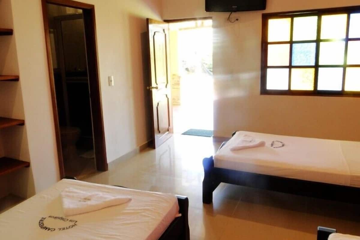 Una habitación de hotel con dos camas, un armario, un televisor y una ventana con persianas.