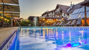 Una piscina techada, una piscina al aire libre de temporada, sombrillas