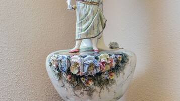 Una fuente de cerámica decorativa con una figura, sobre una mesa de madera frente a una pared lisa.