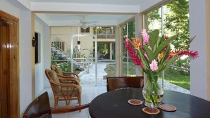 A dining area with a round table, chairs, and a vase of flowers. There is a staircase leading to an upper level. - Villas Pico Bonito (La Ceiba)