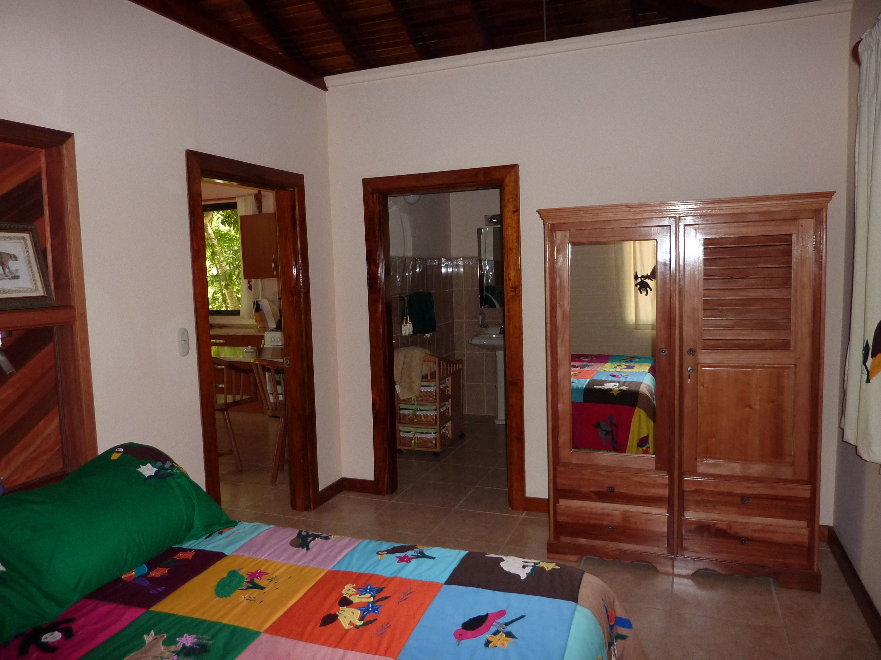Un dormitorio con cama, armario de madera y sofá verde.