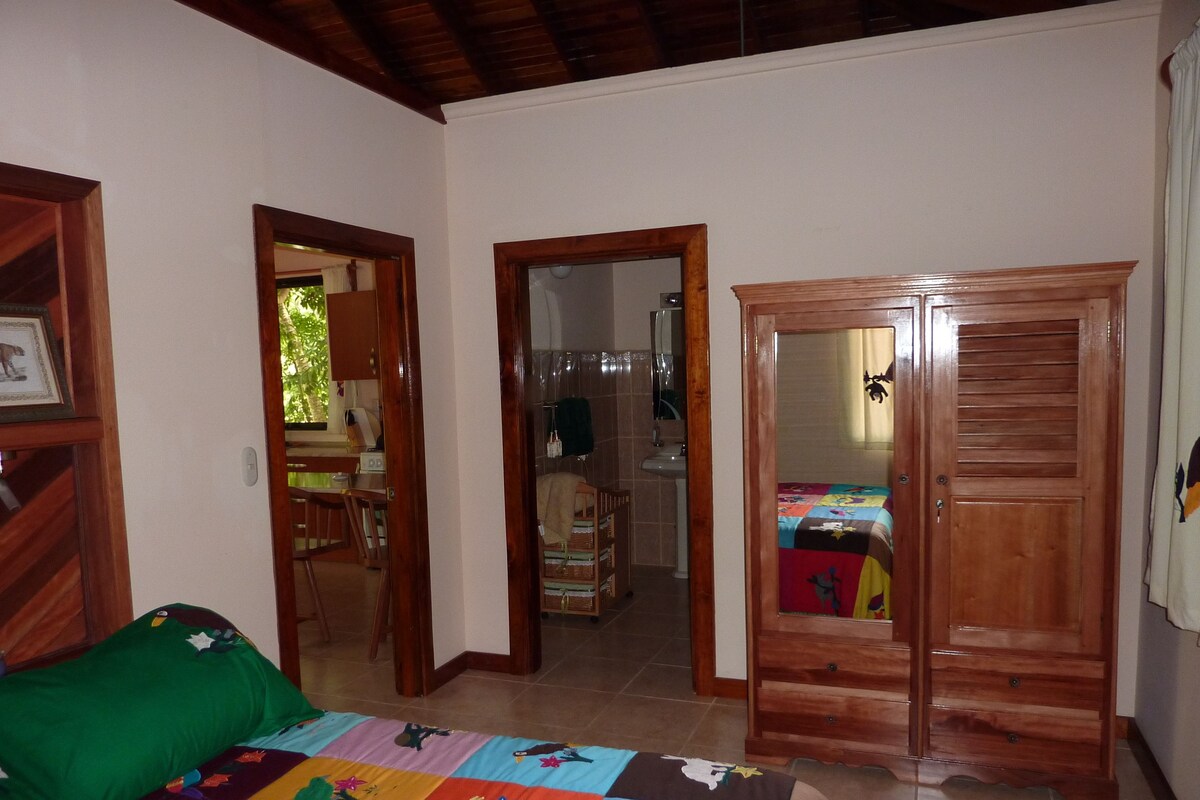 A bedroom with a bed, a wooden wardrobe, and a green sofa.