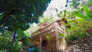 A two-story building with a balcony, surrounded by lush greenery and stone steps. - Villas Pico Bonito (La Ceiba)