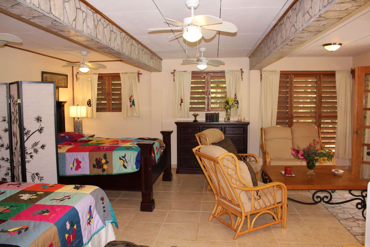 Quarto com cama, cadeira, mesa e ventilador de teto.