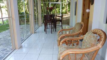 Un patio cubierto con mobiliario de mimbre, una mesa de comedor y sillas.