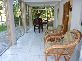 Un patio cubierto con mobiliario de mimbre, una mesa de comedor y sillas.