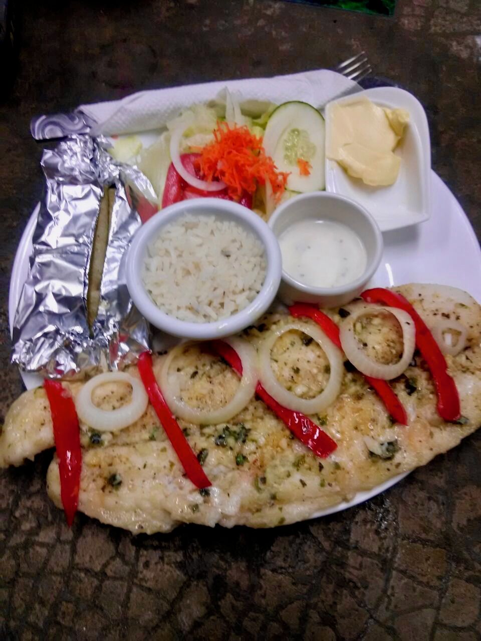 Un plato con pescado, verduras y arroz.