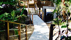 A thatched-roof structure with a wooden deck and a stone pathway leading to it. - Villas Pico Bonito (La Ceiba)