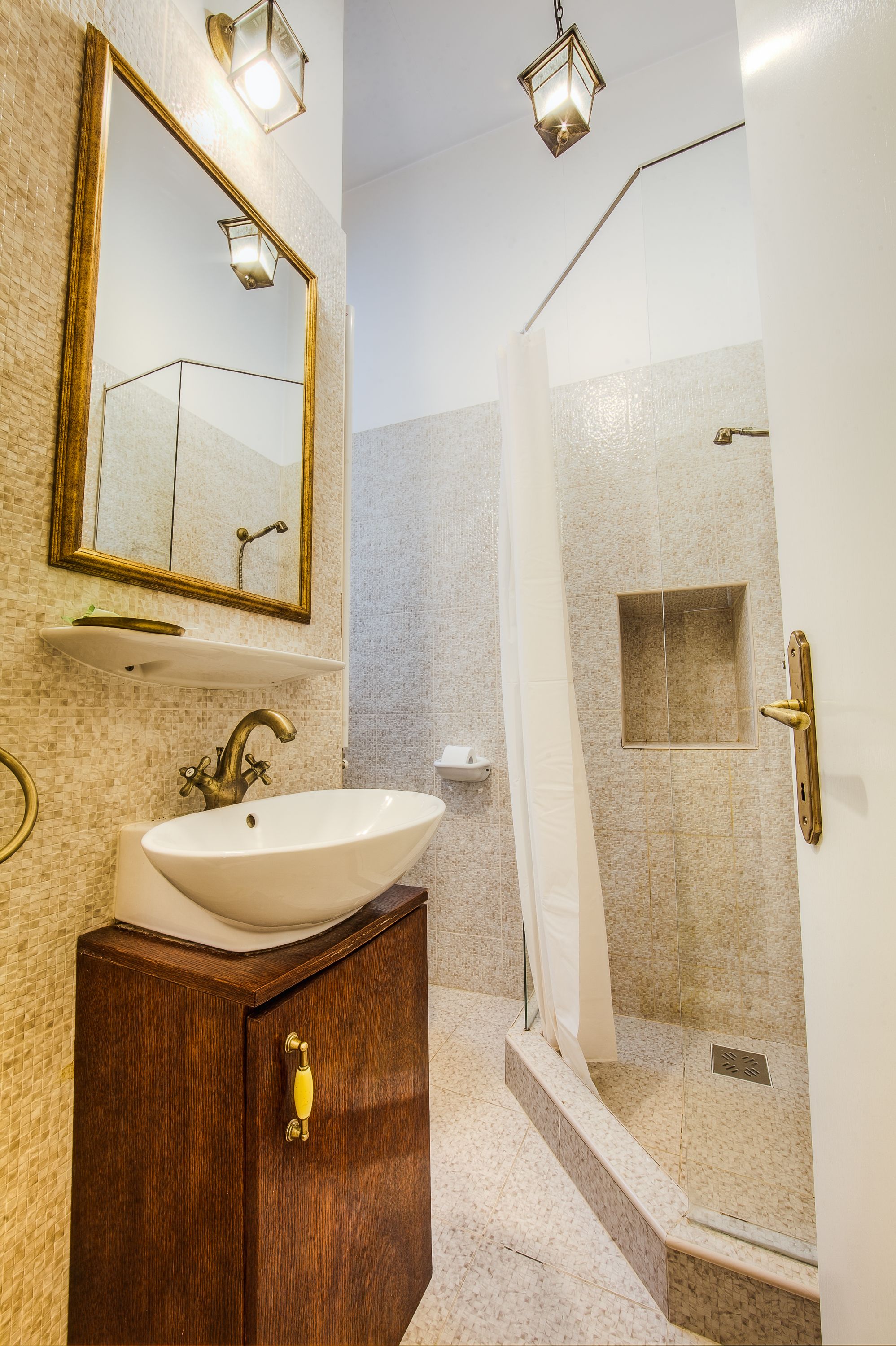 Un baño con un espejo grande, un lavamanos y cabina de ducha.