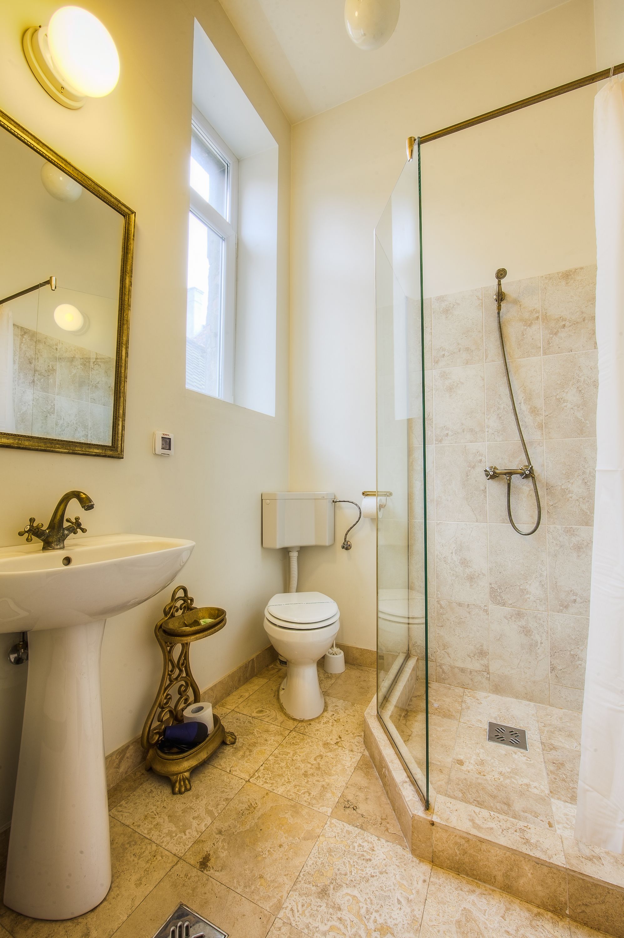 A bathroom with a pedestal sink, toilet, and glass-enclosed shower.