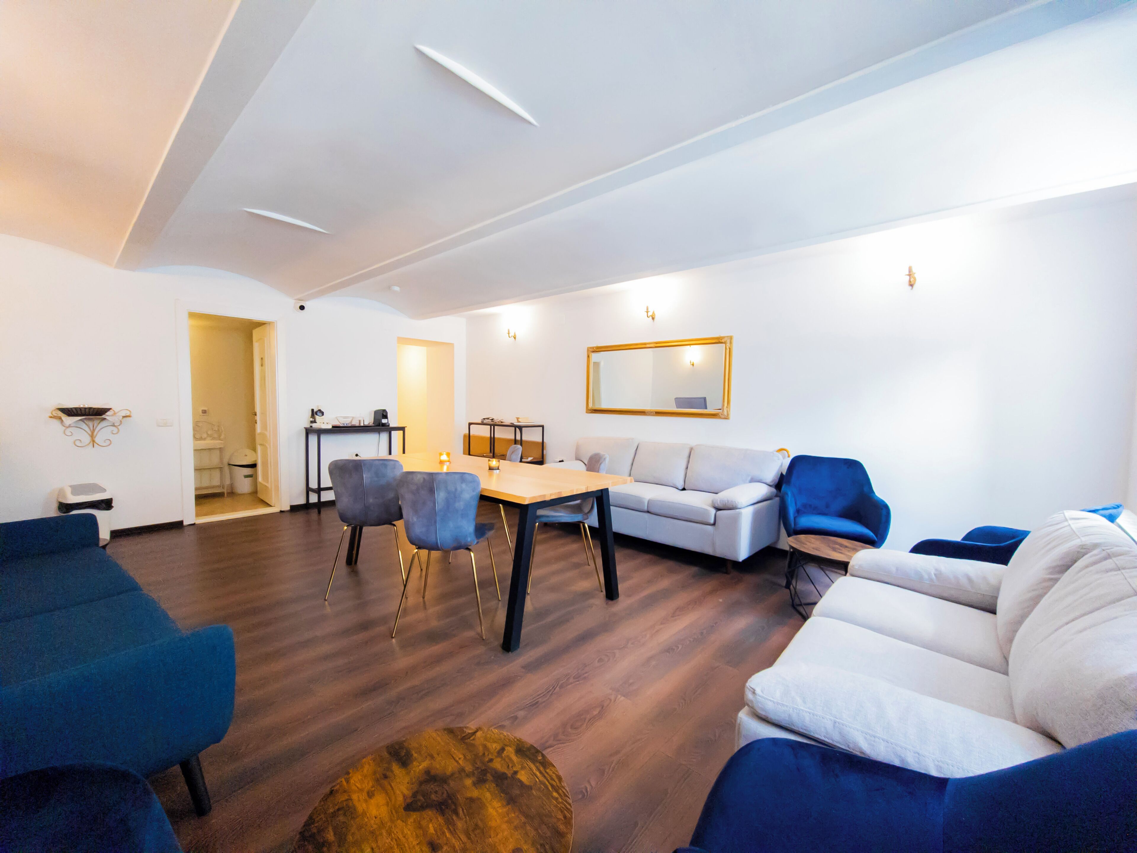 A modern living room with a sofa, chairs, a coffee table, and a dining table.