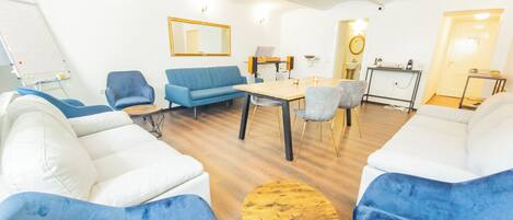 Una sala de estar moderna con un sofá, sillas, una mesa de centro y un comedor.