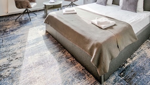 A modern bedroom with a large bed, a desk, two chairs, and skylights. - Residence Central Annapolis (Brasov)