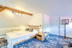 A bedroom with a bed, bedside table, lamp, and a mirror on the wall.