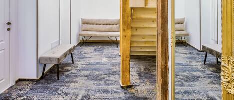 A room with a wooden staircase, a bench, and a chandelier.